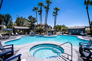 A swimming pool surrounded by palm trees and lounge chairs.