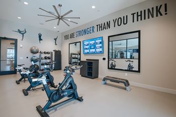 Yoga and spin studio with a row of stationary bikes and a TV screen on the wall at Level 25 at The Curve by Picerne, Las Vegas, NV, 89148