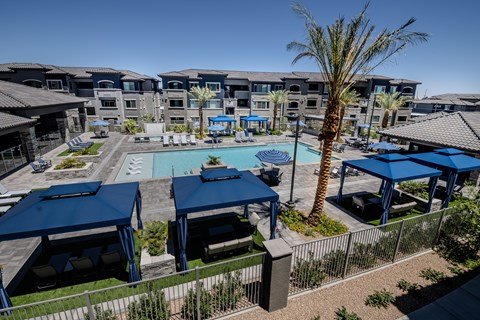 A pool surrounded by blue umbrellas and chairs.