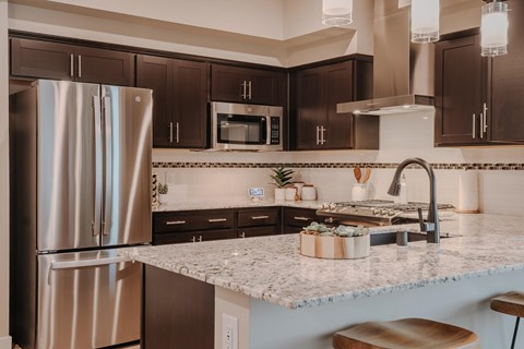 A modern kitchen with a granite countertop and stainless steel appliances.