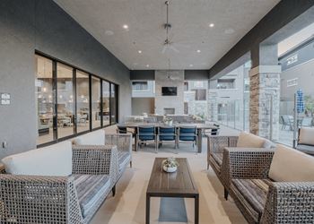 Modern outdoor living space with a dining table and chairs at Level 25 at The Curve by Picerne, Las Vegas