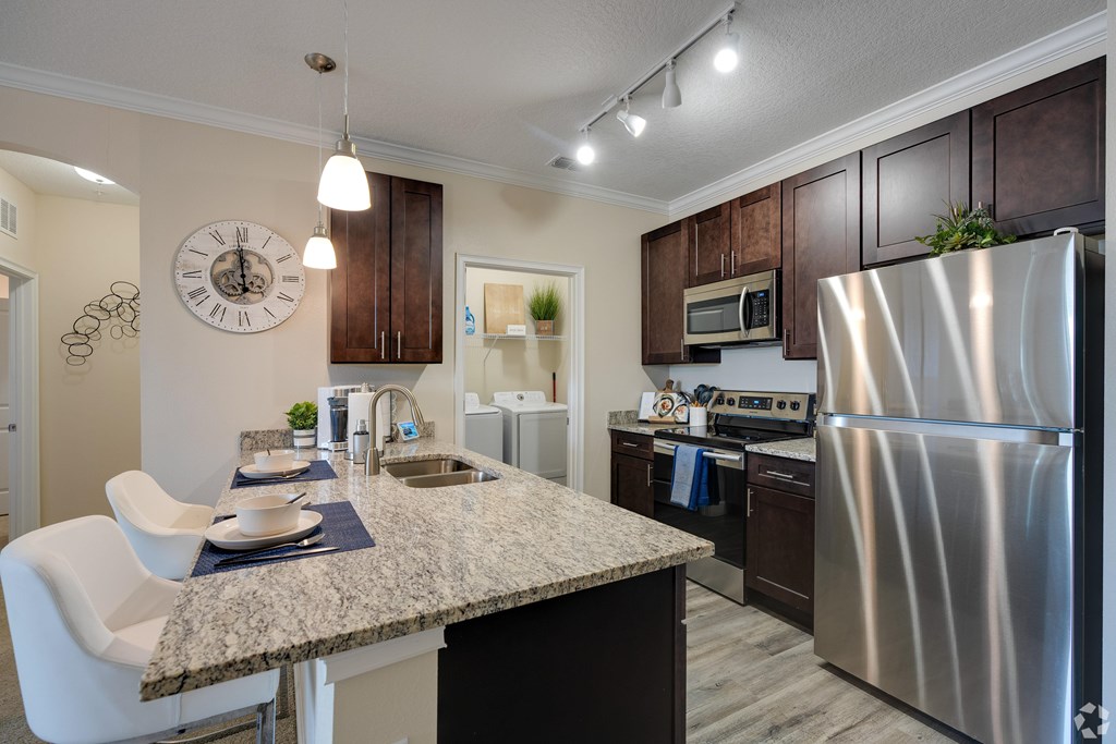 A kitchen with a granite countertop and stainless steel appliances.