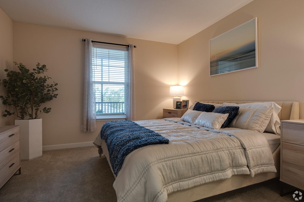 A bedroom with a large bed and a painting on the wall.