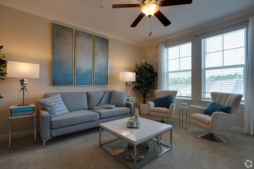 A living room with a grey couch, a white coffee table, and a ceiling fan.