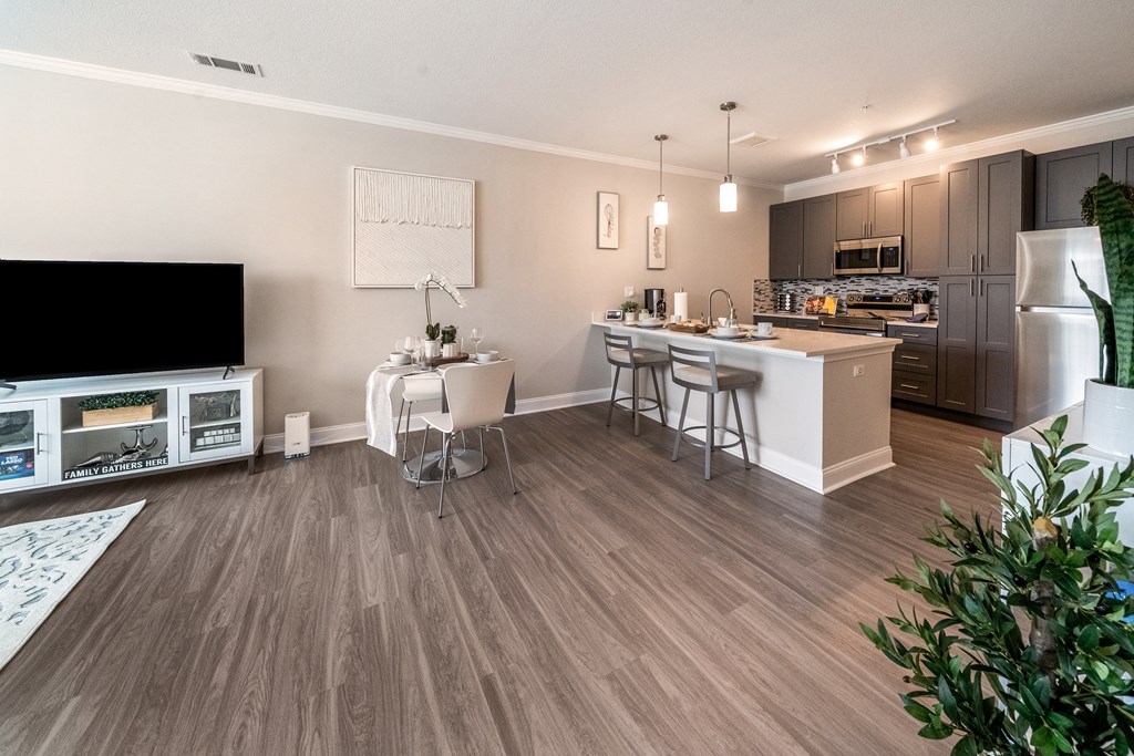 an open kitchen and living room with a dining area and a large tv