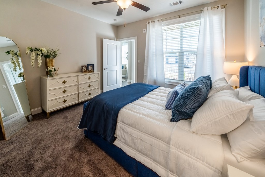 a bedroom with a bed and a dresser and a ceiling fan