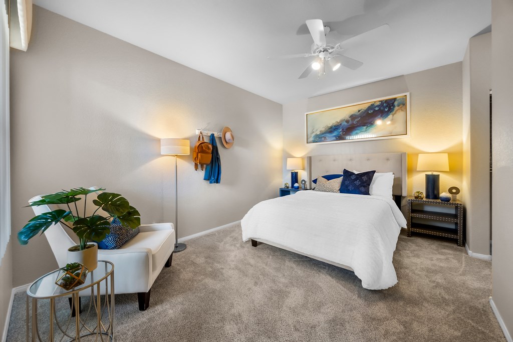 A bedroom with a white bed and a painting on the wall at The Equestrian by Picerne Apartments, Nevada