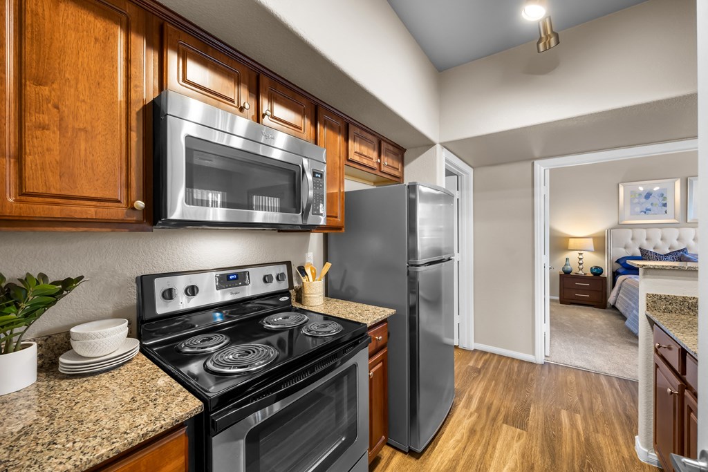 A kitchen with a black stove top oven and a black microwave above it. at The Equestrian by Picerne Apartments, Nevada
