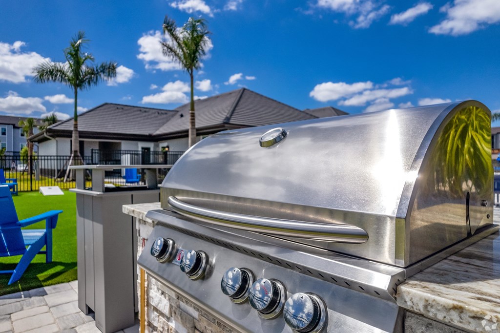 a stainless steel barbecue grill with a palm tree in the background at The Oasis at Manatee River, Bradenton, FL, 34211