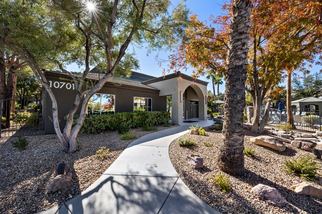 A house numbered 10701 is surrounded by trees and rocks. at The Equestrian by Picerne Apartments, Henderson