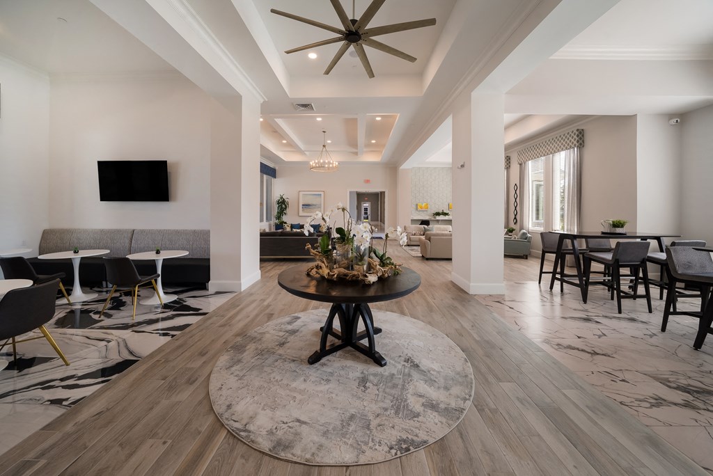a living room with tables and chairs and a ceiling fan
