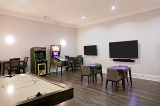 a living room with tables and chairs and a tv and games on the wall