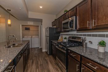 redesigned kitchen with granite countertops and stainless steel appliances and wooden cabinets at Level 25 at Cactus by Picerne Apartments, Las Vegas, Nevada