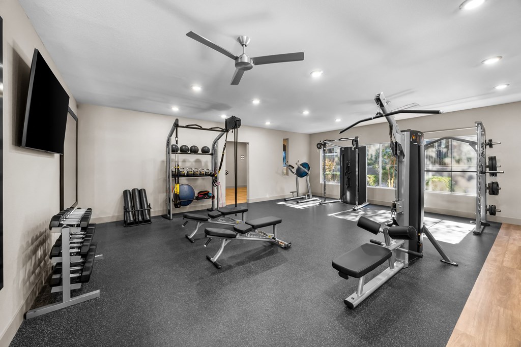 A spacious home gym with a variety of equipment including a squat rack, bench, and weights. at The Equestrian by Picerne Apartments, Nevada