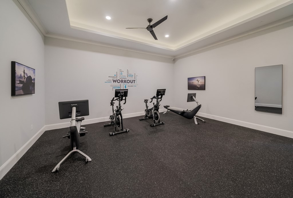 a gym with treadmills and other exercise equipment in a room with white walls