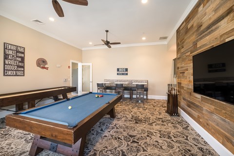 A pool table in a room with a wooden wall and a TV.