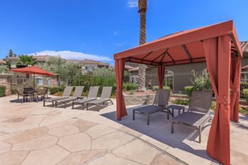 A patio with a red canopy and chairs. at The Fairways by Picerne Apartments, Las Vegas 89141
