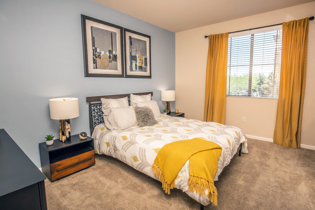 a bedroom with a yellow comforter and yellow curtains