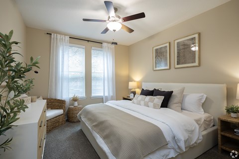 A bedroom with a large bed and a ceiling fan.