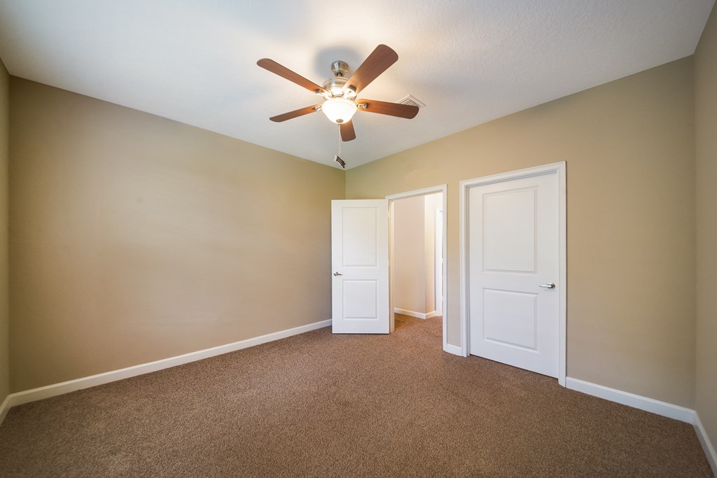 an empty living room with a ceiling fan and two doors at The Oasis at Highwoods Preserve, Tampa, FL, 33647