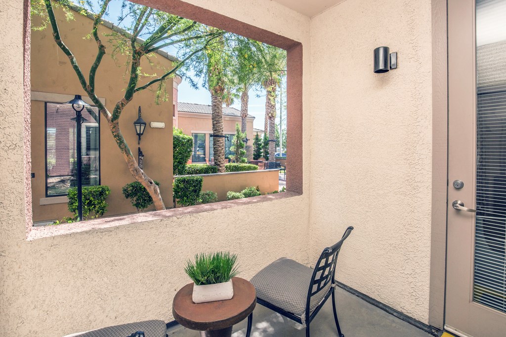 a patio with a chair and a table and a large window