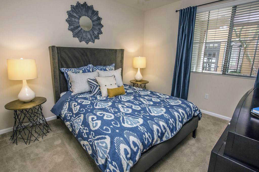 a bedroom with a bed with blue and white bedding and a window