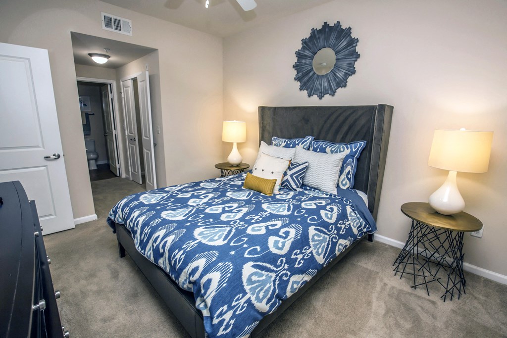 a bedroom with a bed with blue and white comforter and pillows