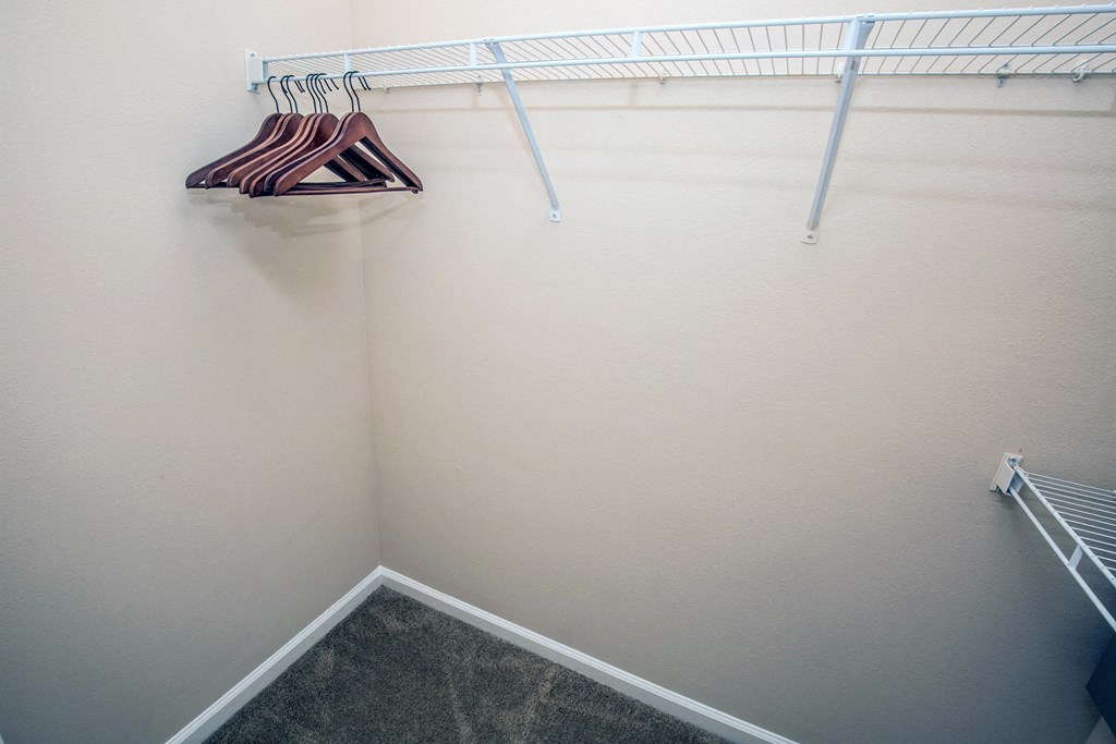 a walk in closet with a white wall and a rack and hangers
