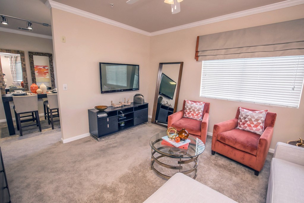 a living room with two red chairs and a glass coffee table