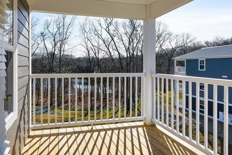 a deck with a blue house and trees in the background