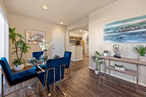 A dining room with a glass table and blue chairs. at The Fairways by Picerne Apartments, Las Vegas, NV, 89141