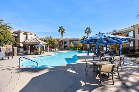A swimming pool with a blue umbrella and chairs around it.