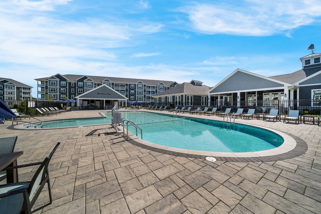 a resort style pool with chairs and a building in the background