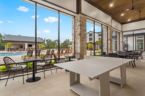 A white table is in the middle of a patio with a pool table and chairs.