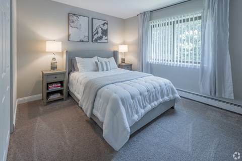 A bedroom with a large bed and two lamps.