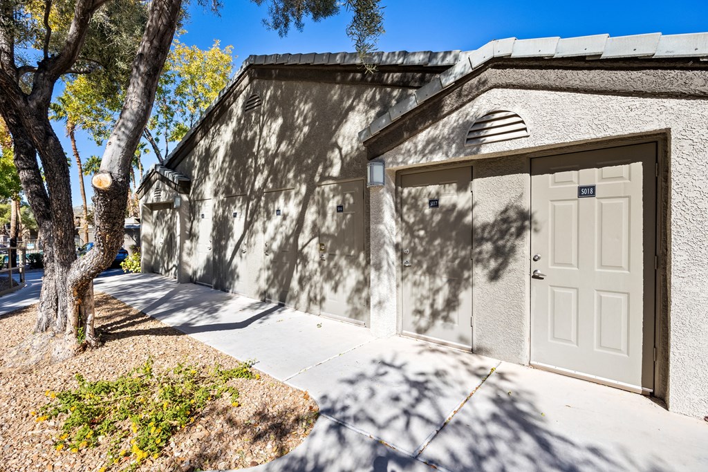 A building with a white door and a tree in front of it. at The Equestrian by Picerne Apartments, Henderson 89052