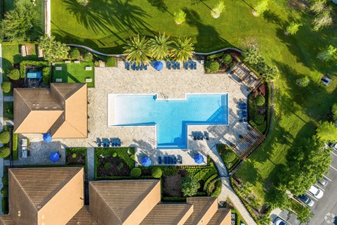 A swimming pool surrounded by a grassy area and a few trees.