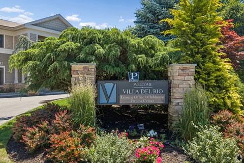 A sign welcoming people to Villa Del Rio is in front of a house.