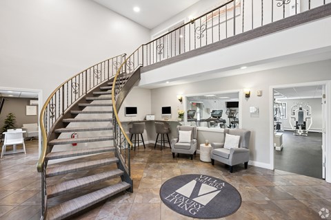 A living room with a staircase and a rug that says "Villa Living".