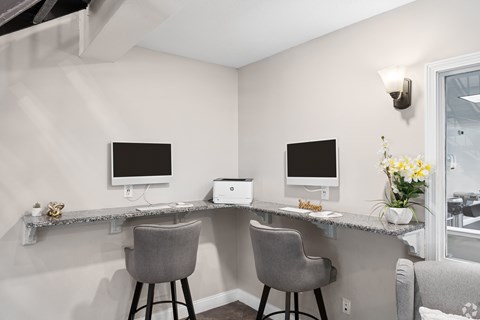 A home office with two computers and a grey chair.