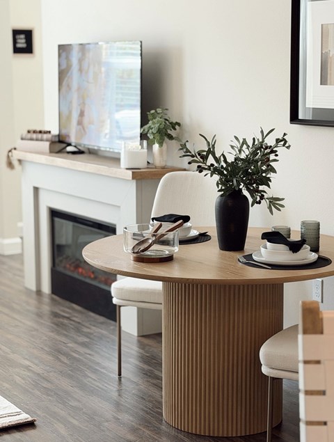 A modern dining room with a fireplace and a TV above it.