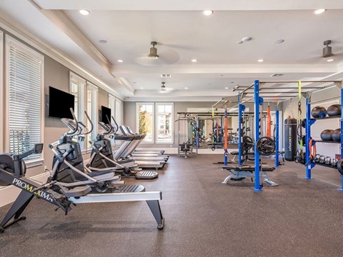 A gym with a variety of equipment including treadmills, weights, and exercise machines.
