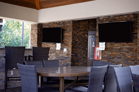 a dining area with a table and chairs and televisions on the wall at The Oasis at Moss Park, Orlando