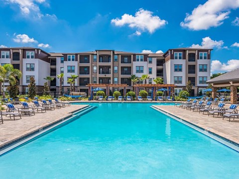 A large swimming pool in front of apartment buildings.