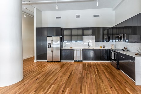 a kitchen with black cabinets and stainless steel appliances and a wooden floor