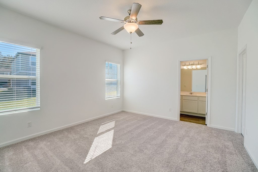 Bedroom with ceiling fan and two windows of the Oak floor plan at Beacon at Clinton Corners in Dade City, FL