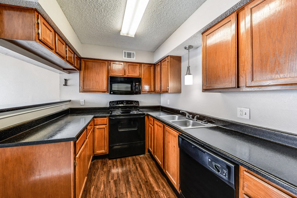 a kitchen with wooden cabinets and black counter tops and a black dishwasher