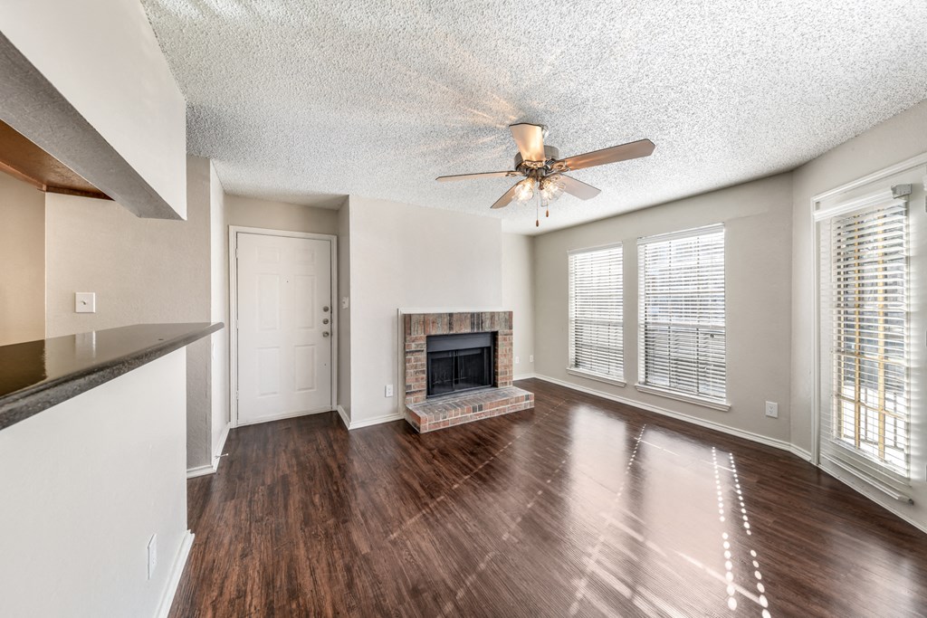 an empty living room with a fireplace and a ceiling fan