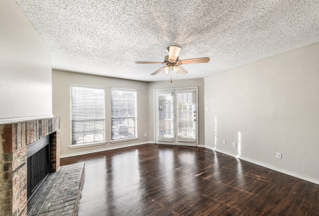 an empty living room with a fireplace and a ceiling fan