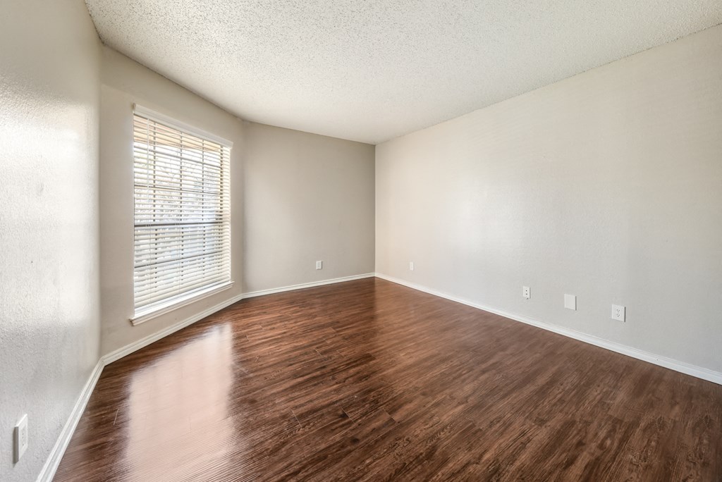 an empty living room with wood floors and a window
